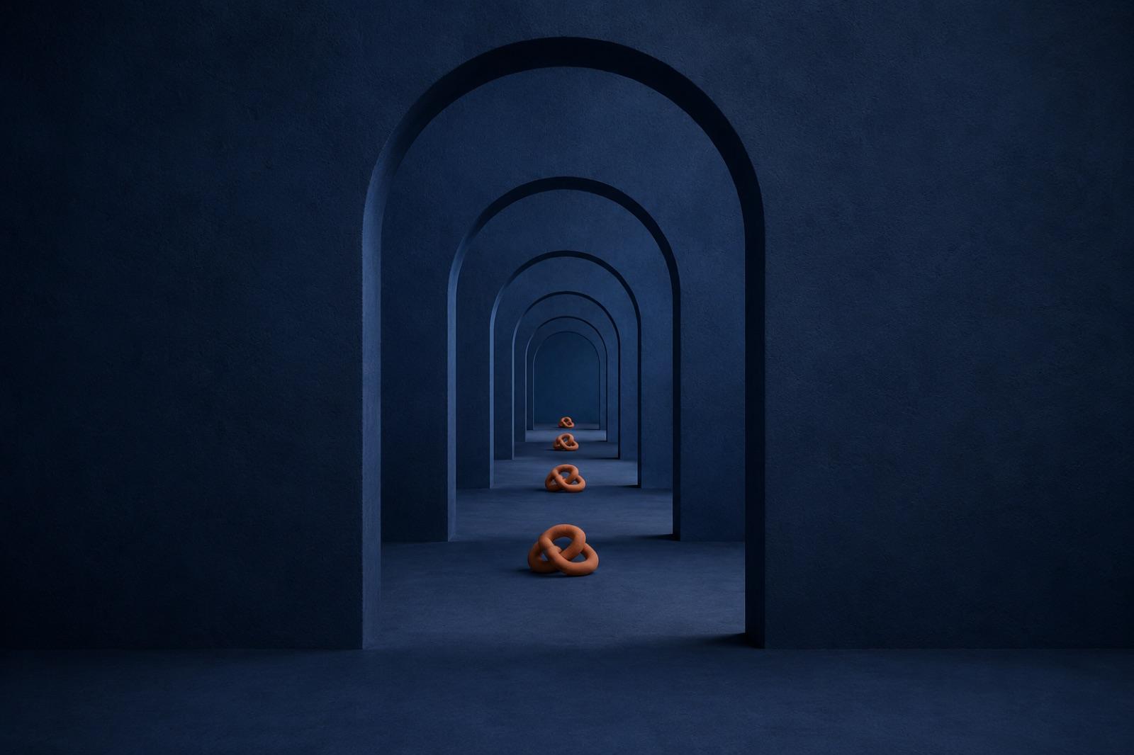 A deep blue corridor of identical receding archways with the same small terracotta knot lying on the floor under every arch
